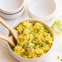 Curried Potato Salad in a bowl with two wooden spoons.