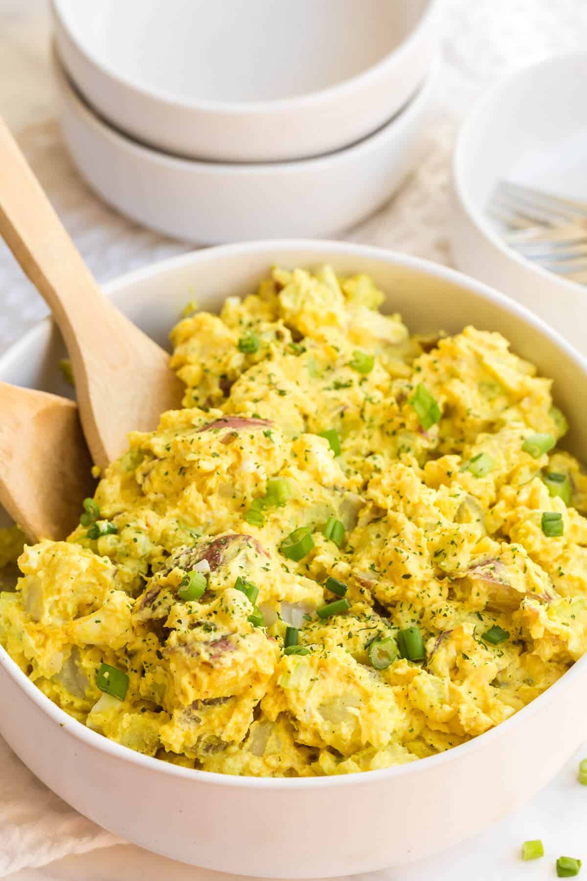 Curried potato salad in a bowl with two spoons.