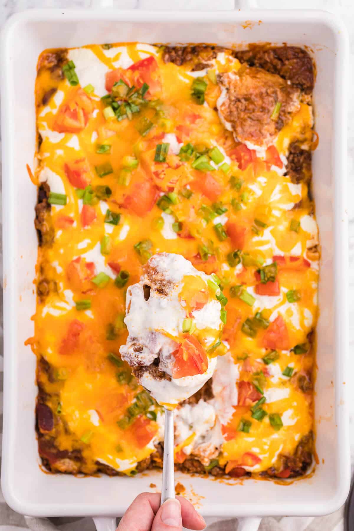 A serving spoon over a pan of taco casserole.