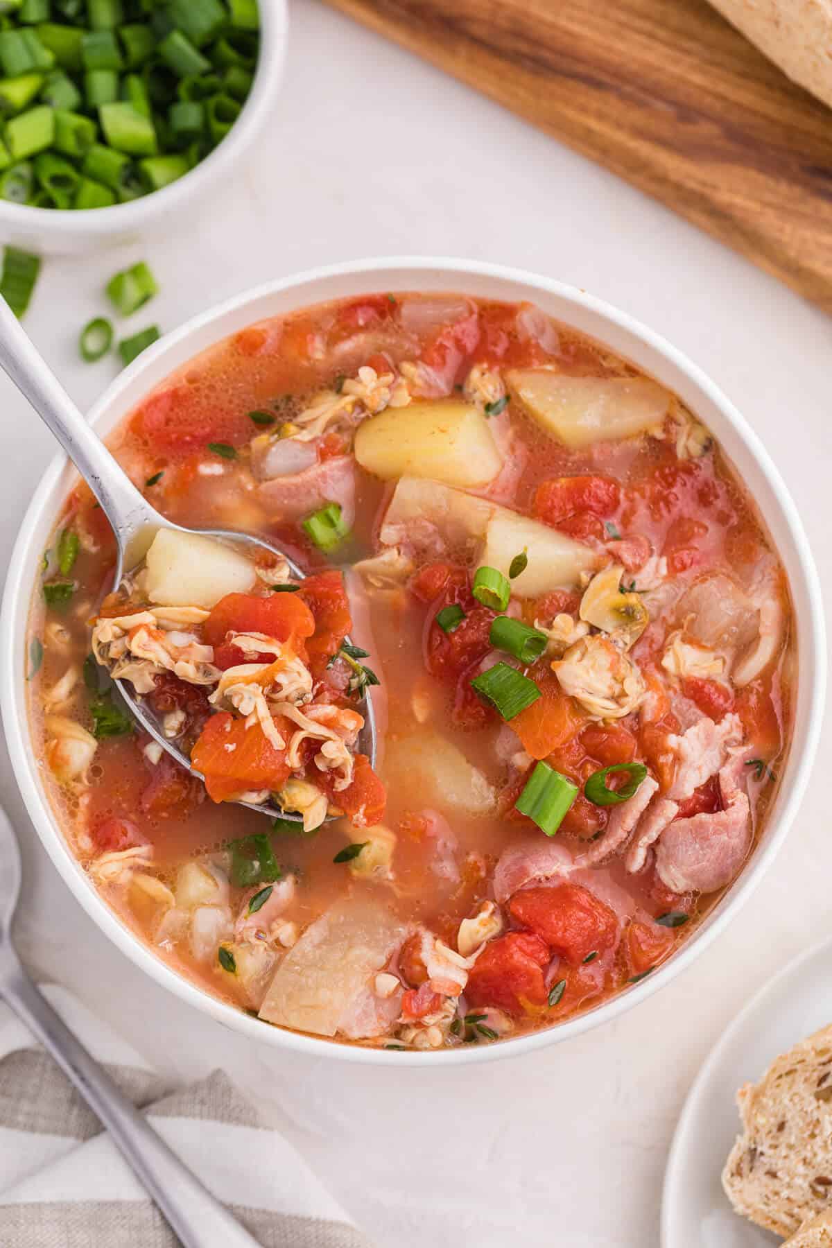 A bowl of Manhattan Clam Chowder with a spoon.