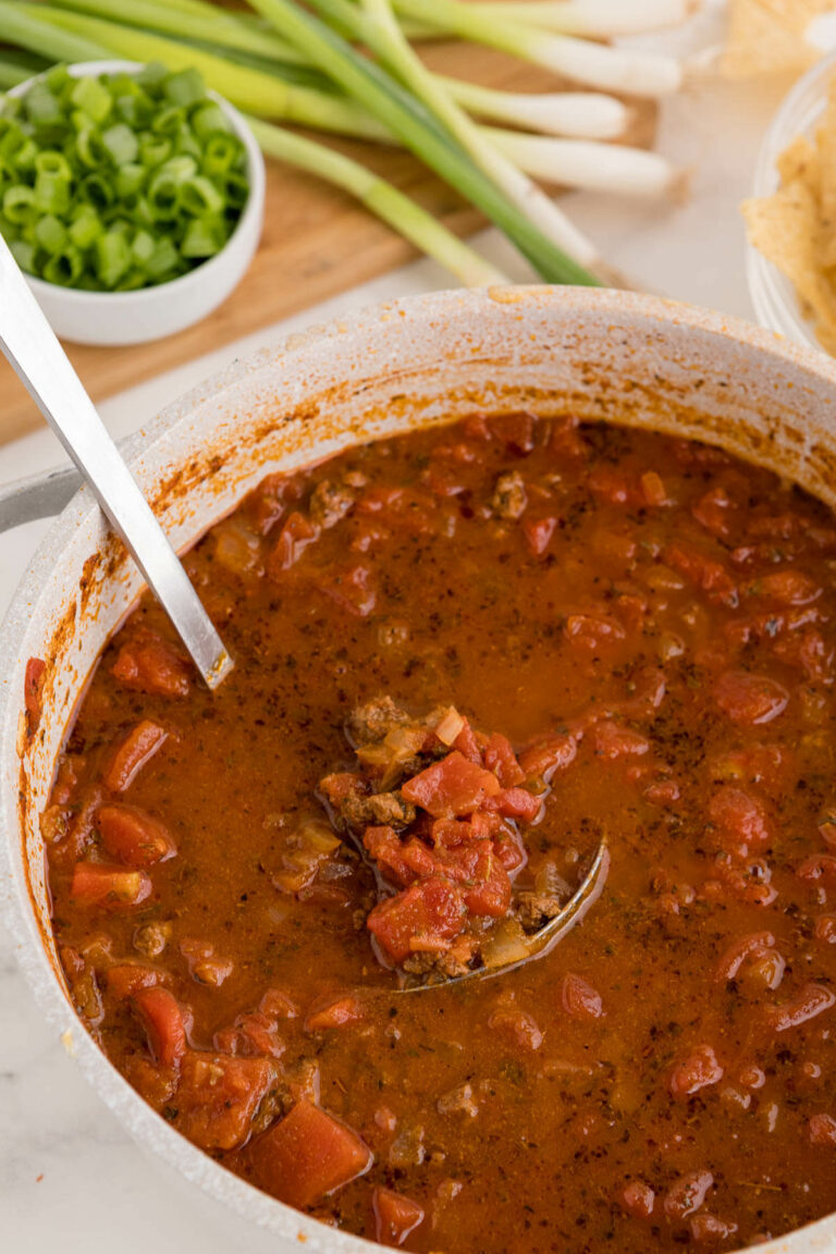 The soup in a pot with a ladle.