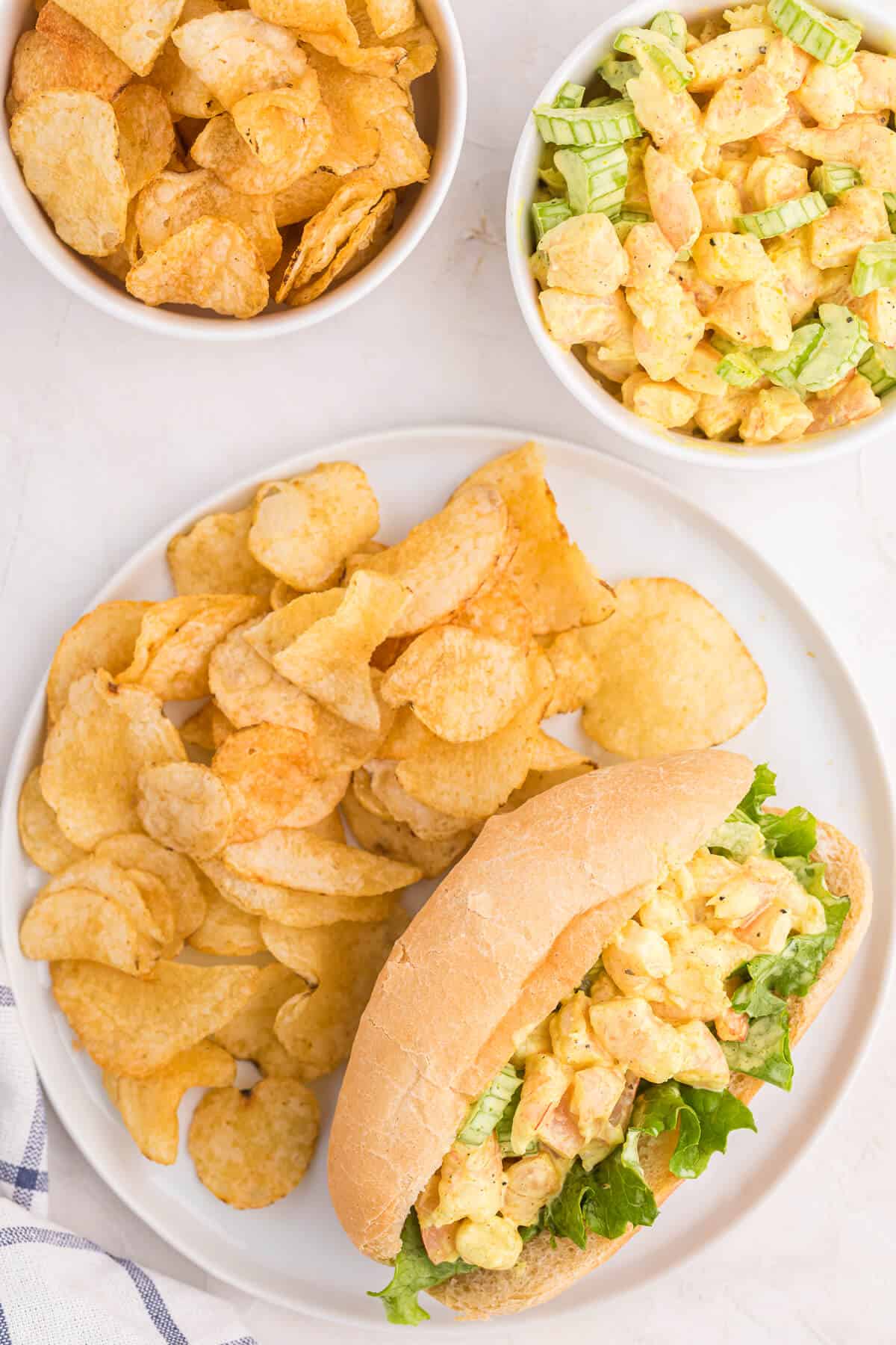 Curried shrimp rolls with potato chips on a plate.