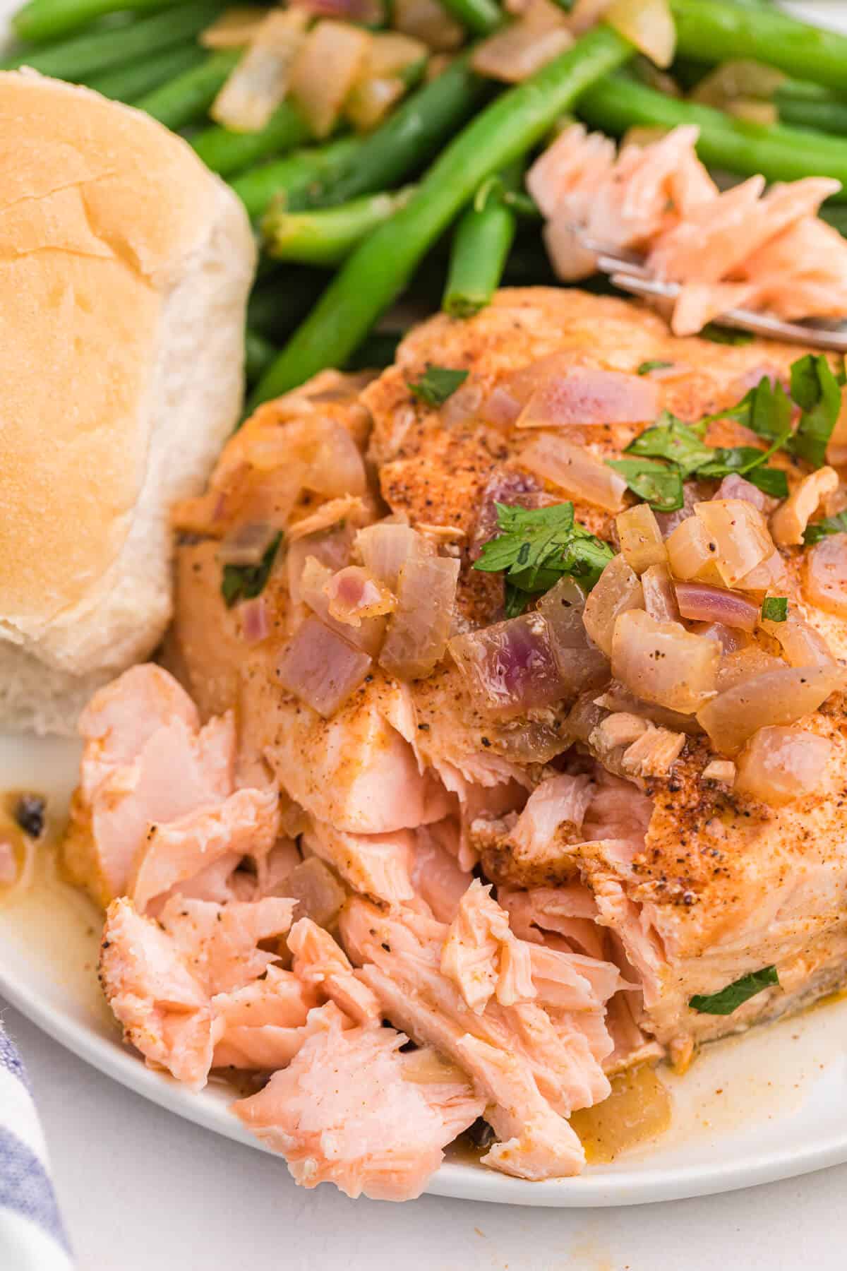 Drunken salmon with bites out of it on a plate.