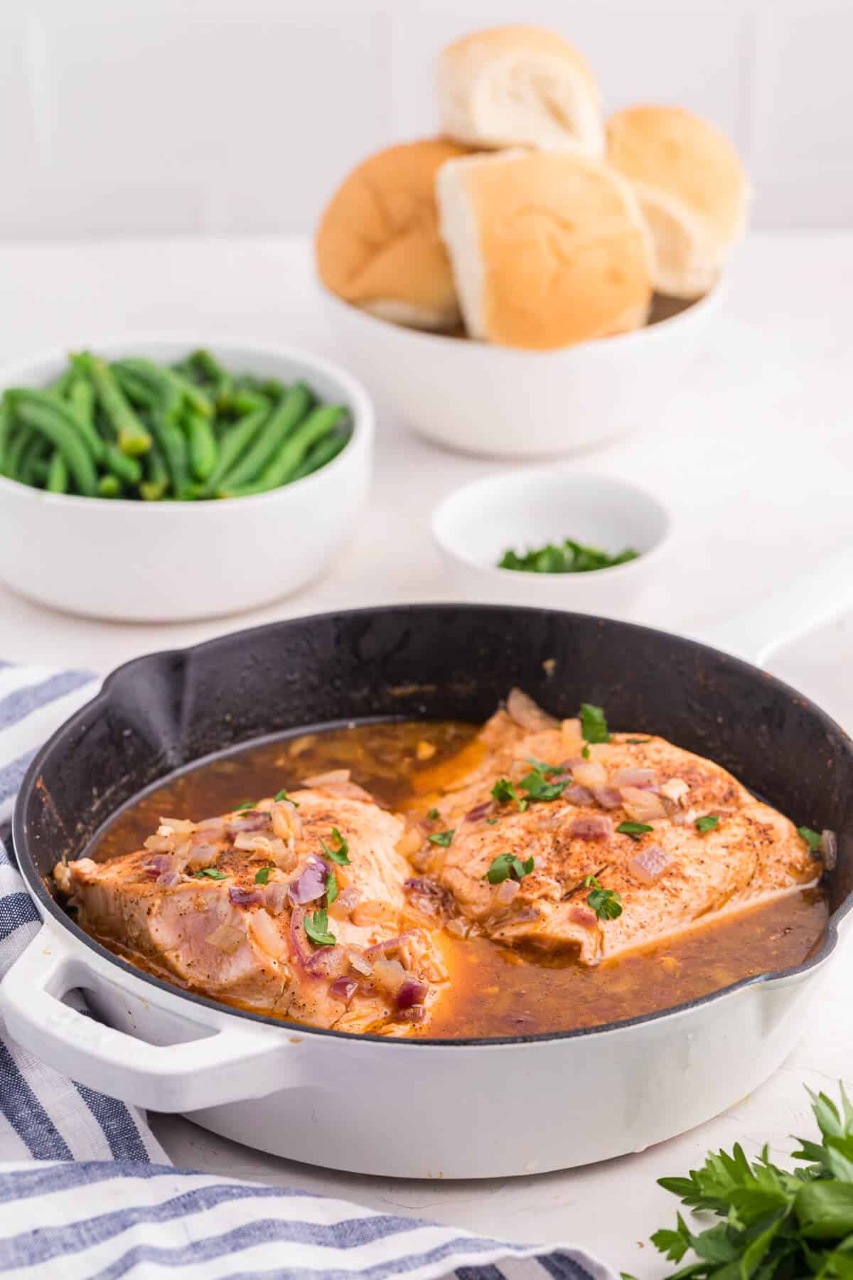 Salmon fillets in beer sauce in a white skillet.