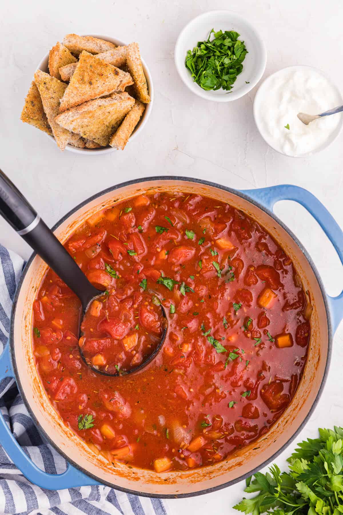 Italian herb soup in a pot with a ladle.