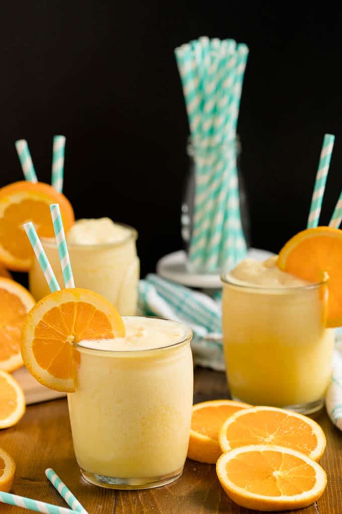 Orange Julius in a glass cup with straws and an orange slice.
