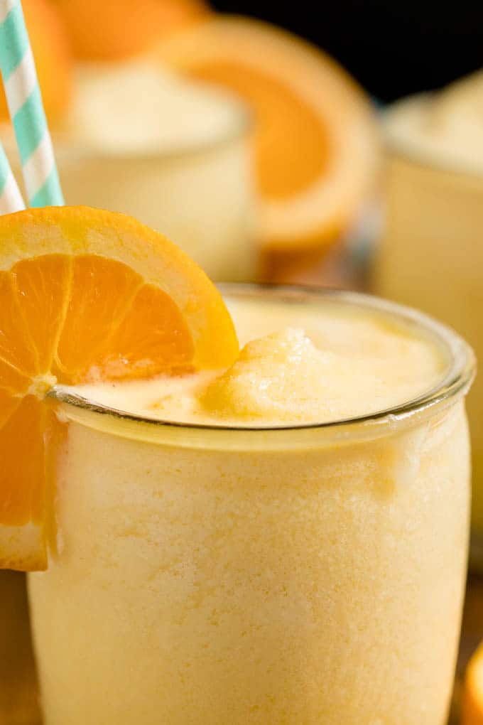 Orange Julius in a glass cup with straws and an orange slice.