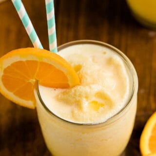 The recipe in a glass with a straw and orange slice on a wooden surface.