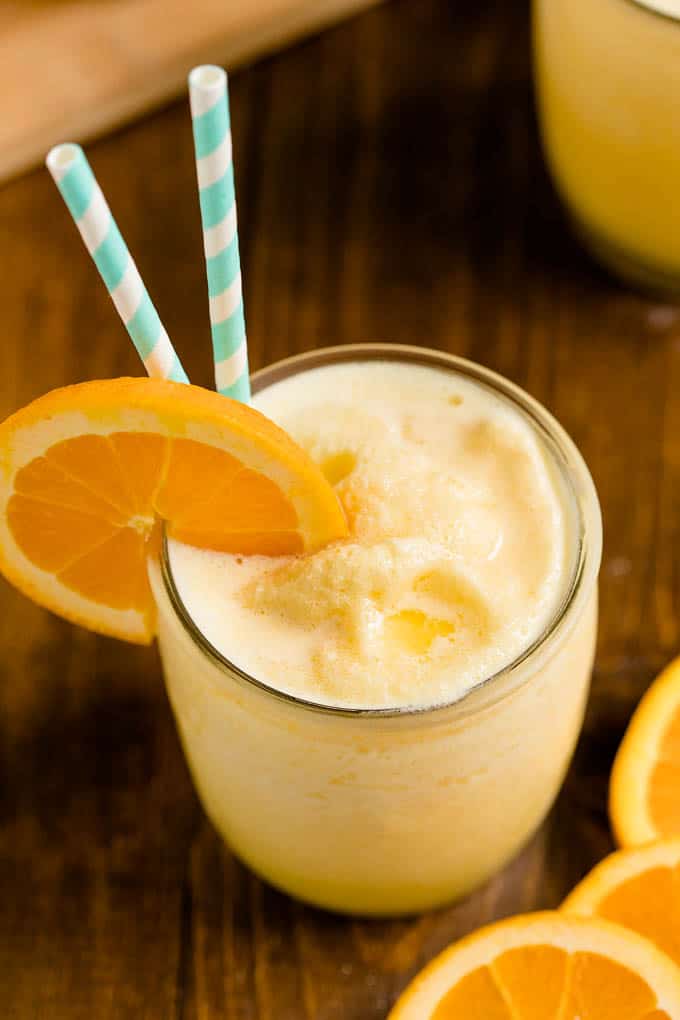 Orange Julius in a glass cup with straws and an orange slice.