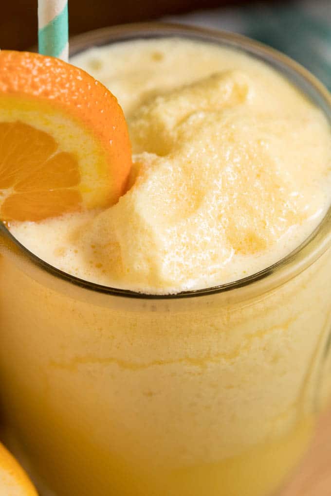 Orange Julius in a glass cup with straws and an orange slice.