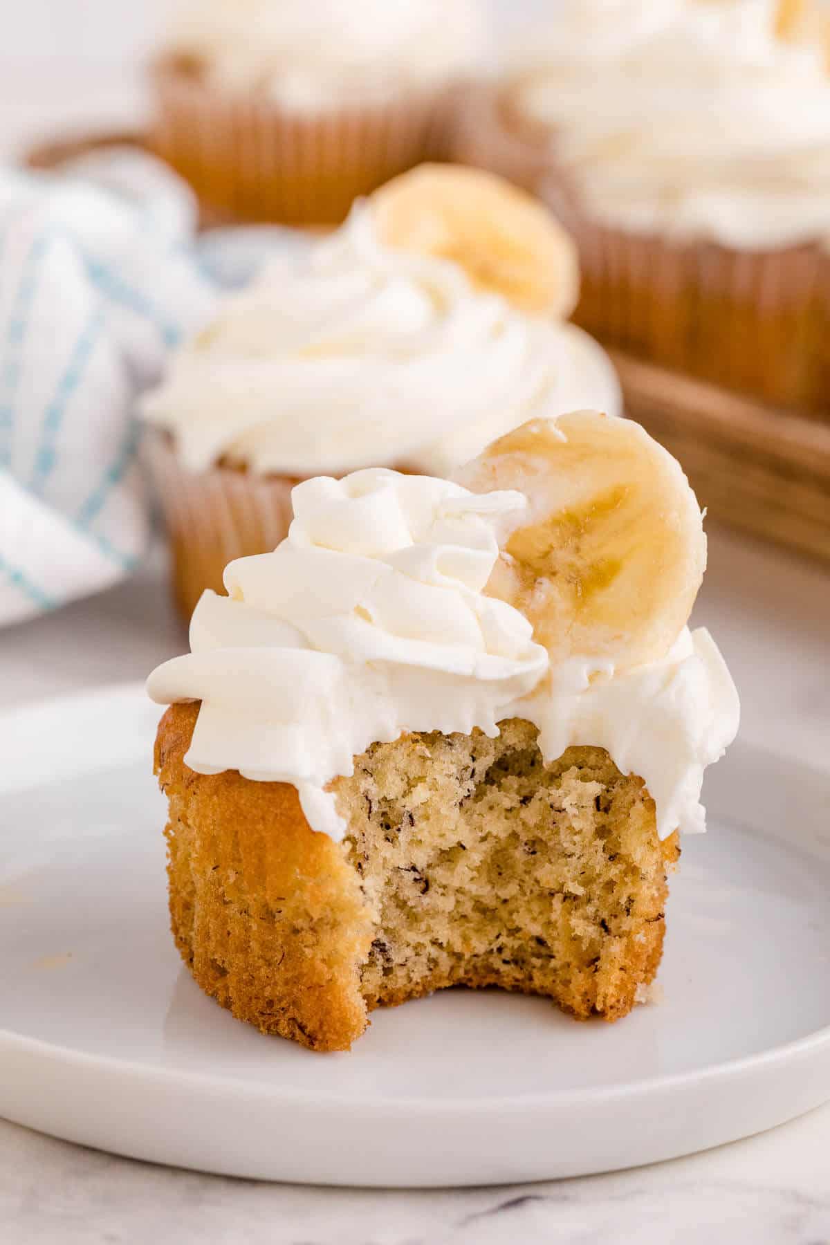 A banana cupcake on a plate with a bite out of it.