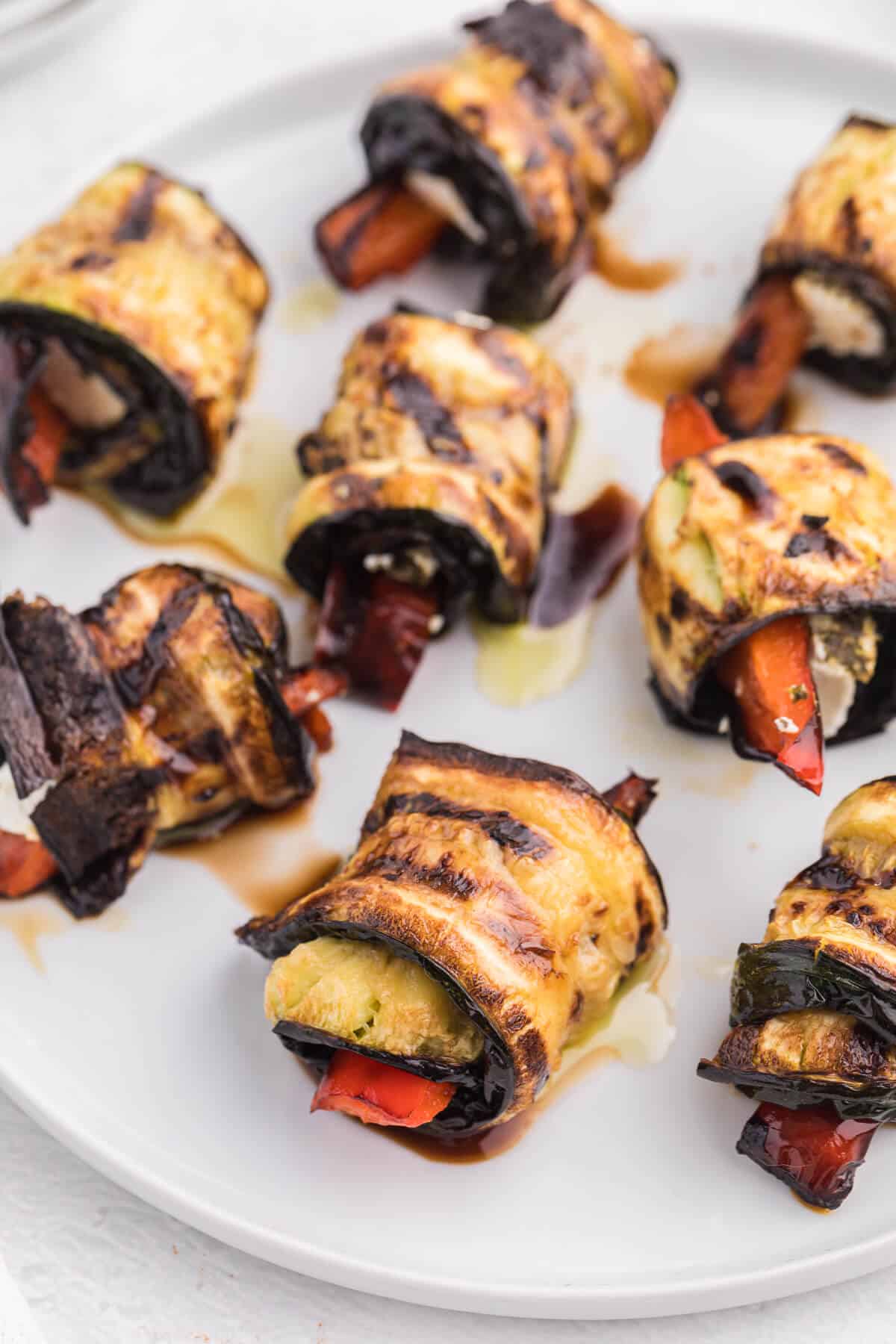 Grilled Zucchini Roll-Ups - A simple, but savory summer appetizer. This easy recipe wraps grilled zucchini strips around herbed goat cheese and grilled red peppers with a finish of extra olive oil and balsamic vinegar. Mmm!