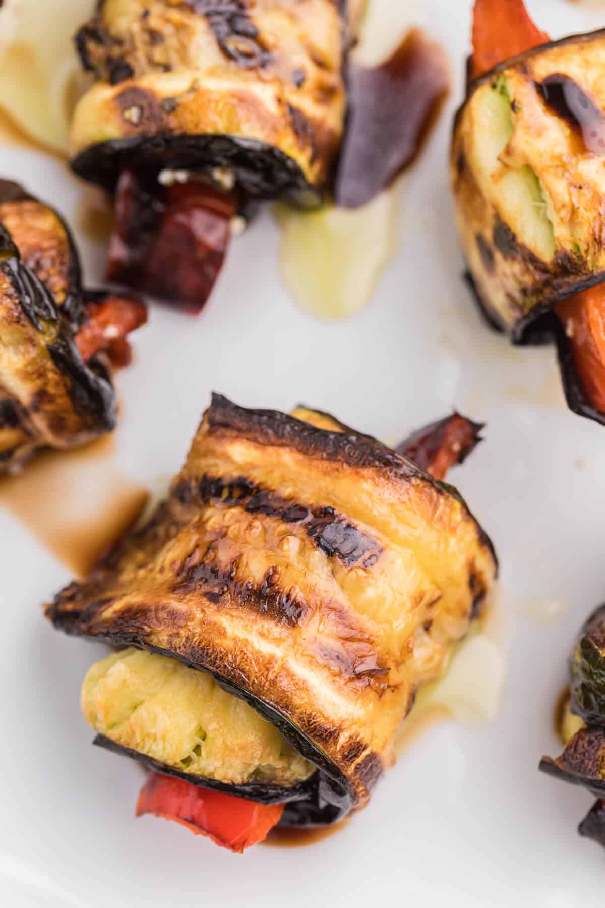 Grilled Zucchini Roll-Ups - A simple, but savory summer appetizer. This easy recipe wraps grilled zucchini strips around herbed goat cheese and grilled red peppers with a finish of extra olive oil and balsamic vinegar. Mmm!