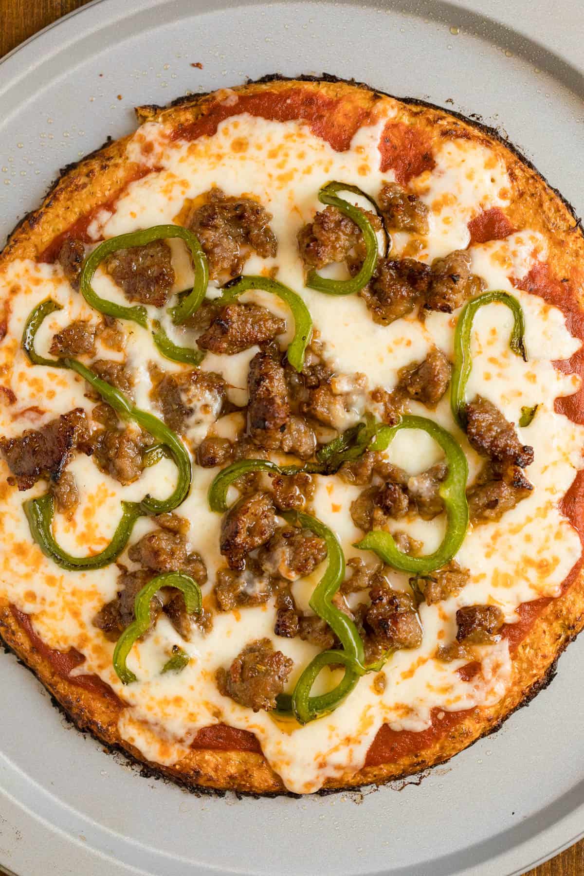 A baked sausage pizza with a cauliflower pizza crust.