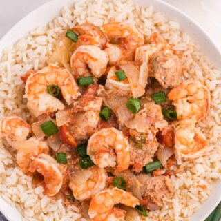 Sausage jambalaya over a bed of rice in a bowl.