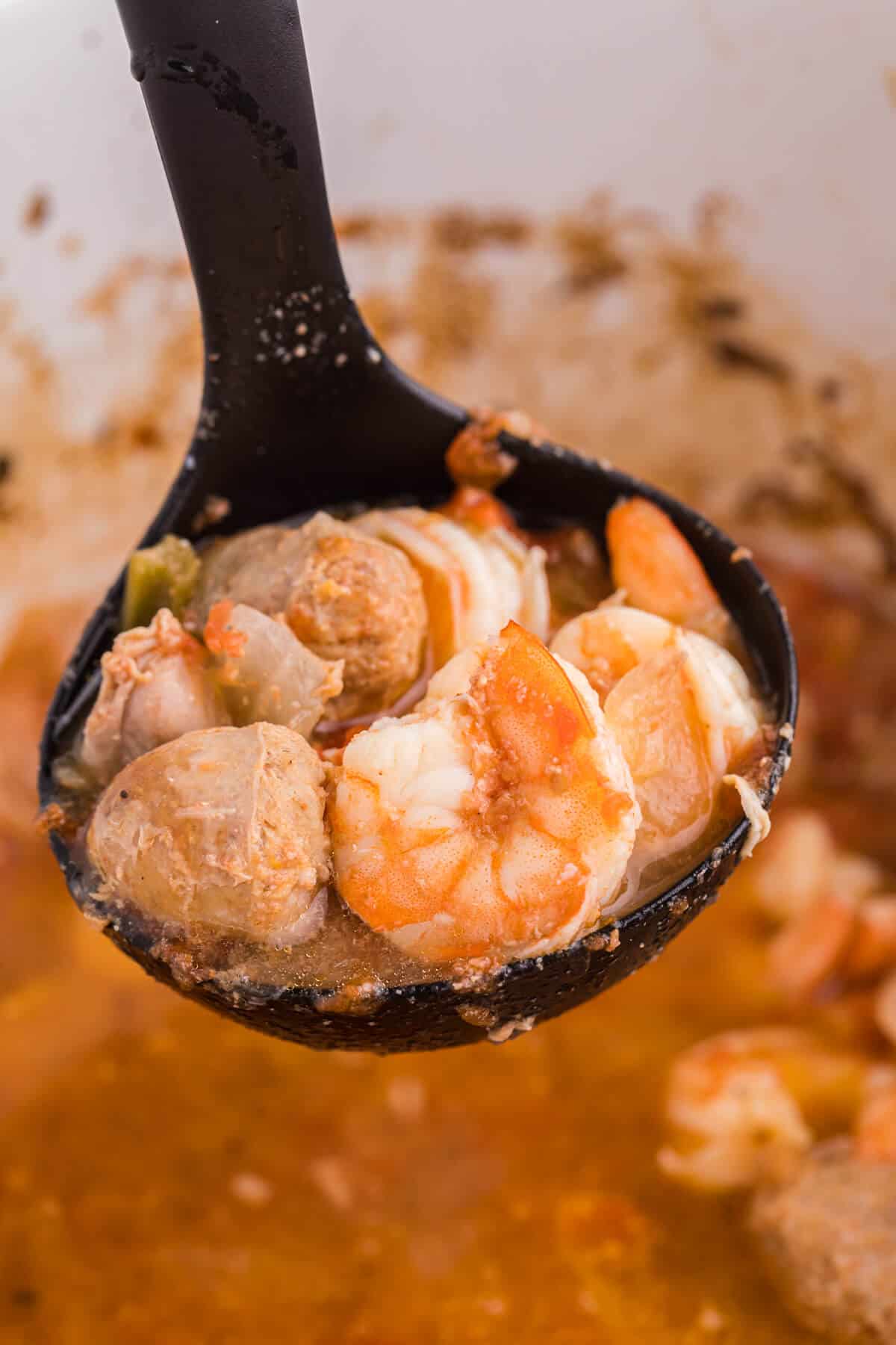 Sausage jambalaya in a black ladle.