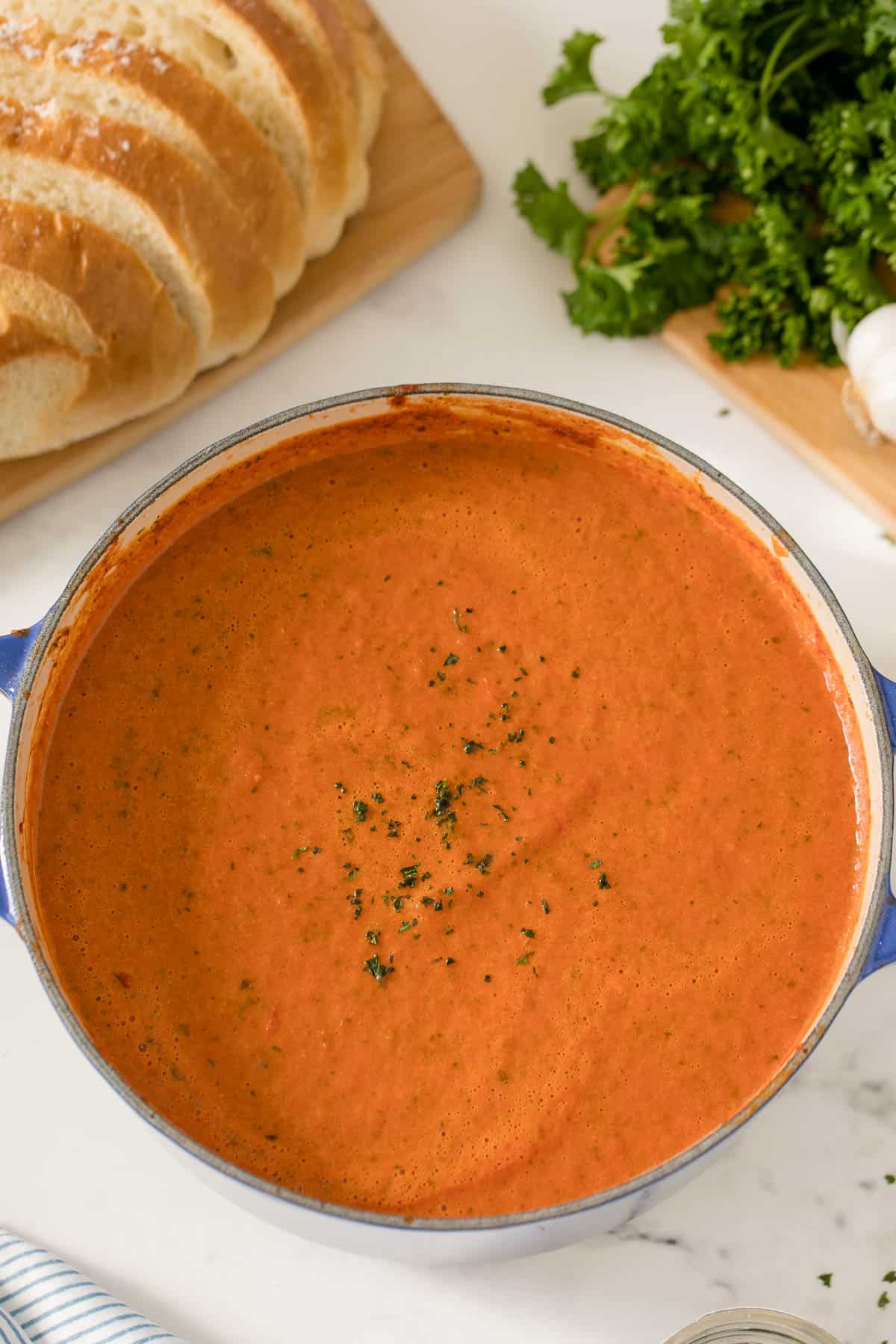 A pot of cream of tomato soup with bread on the side.