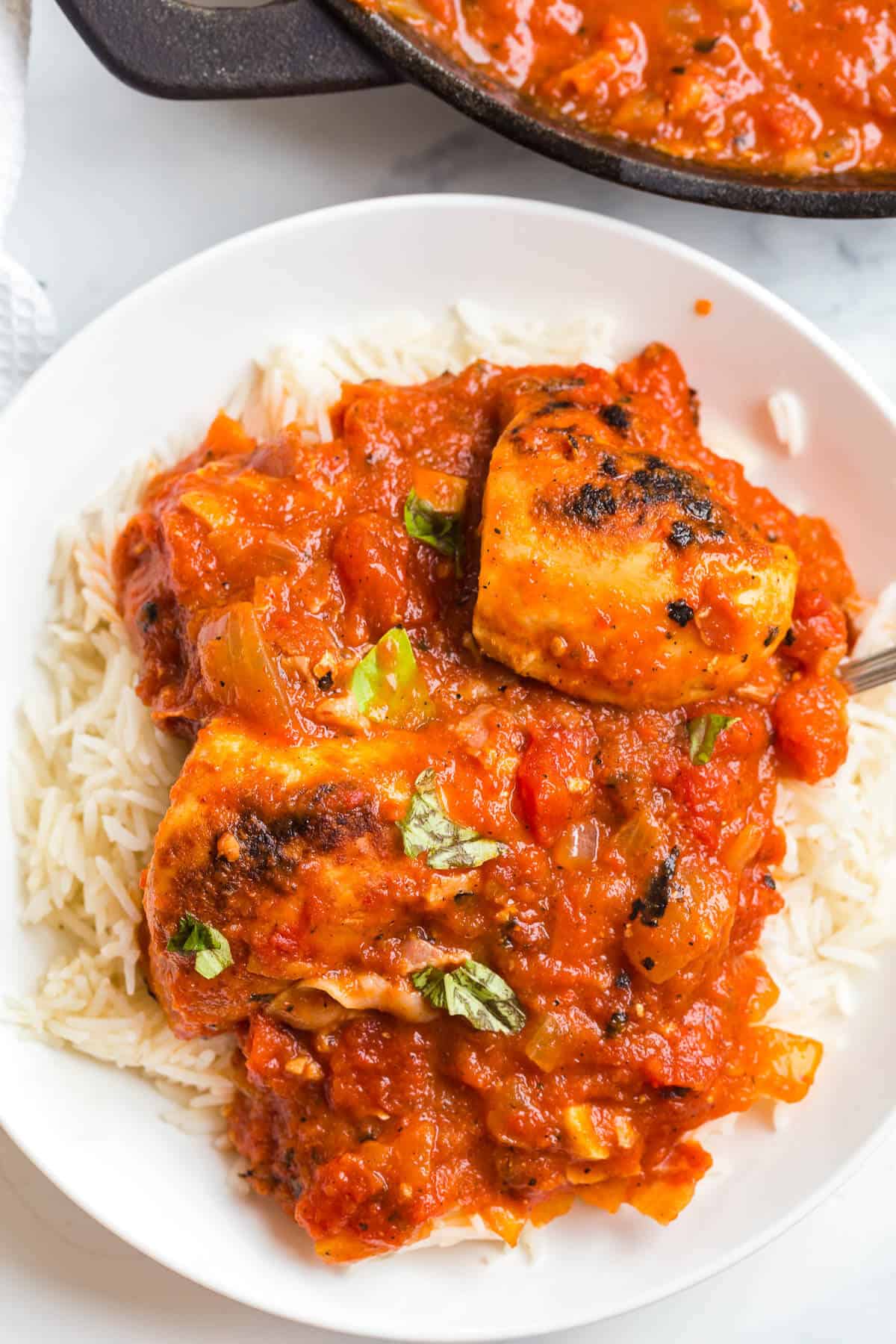 Roasted red pepper chicken served on a plate over rice.