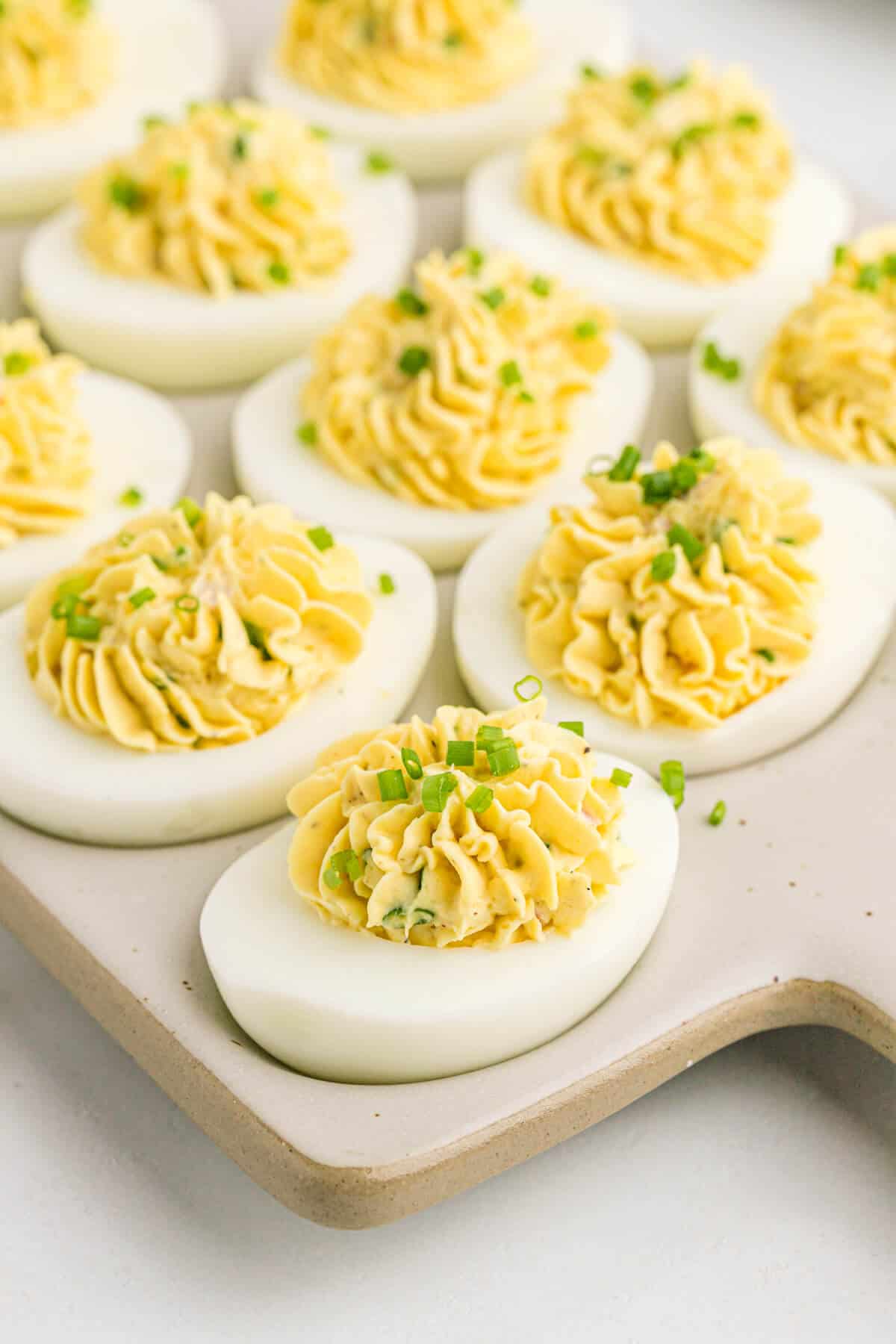 Devilish eggs on a grey cutting board.