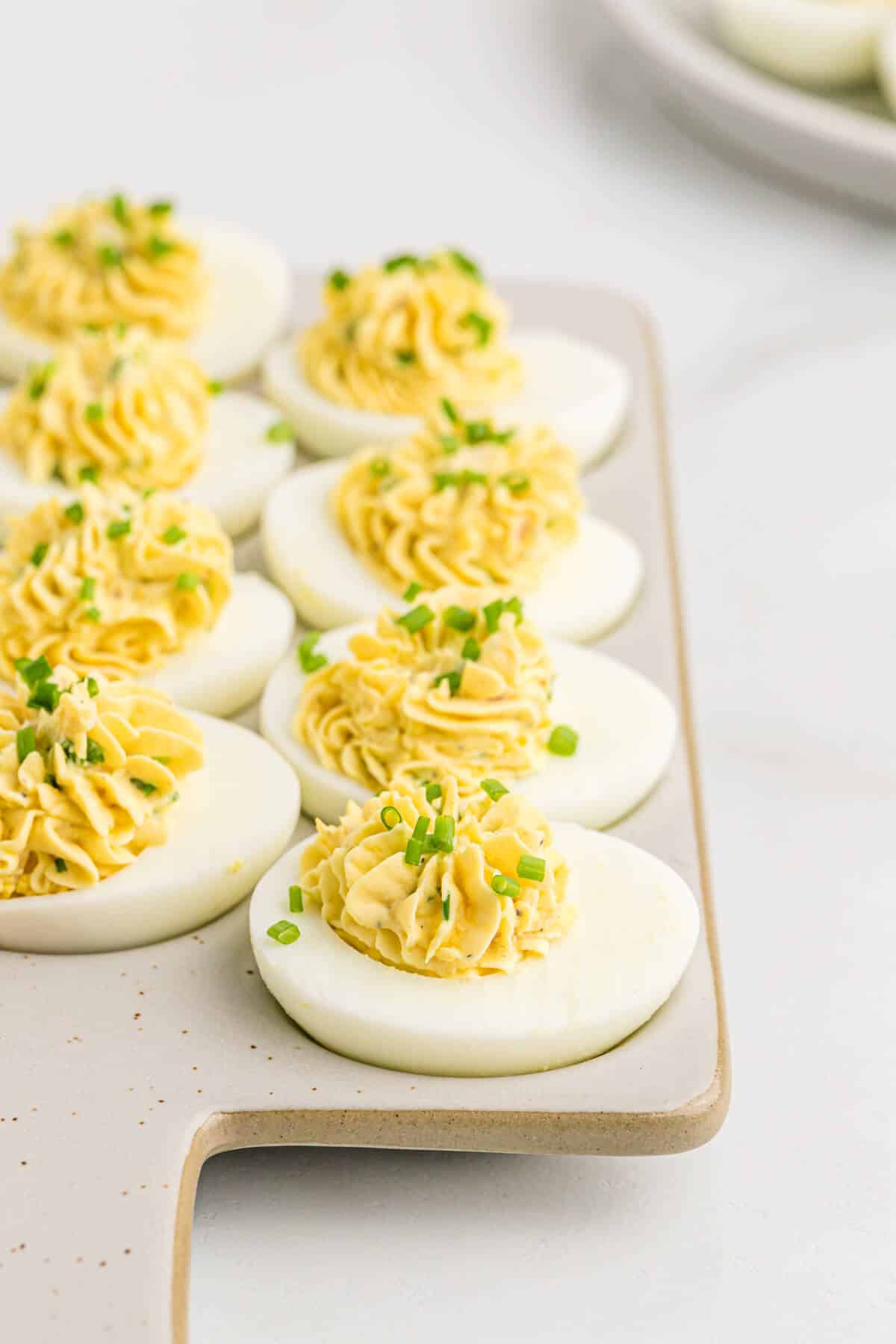 Devilish eggs on a grey cutting board.