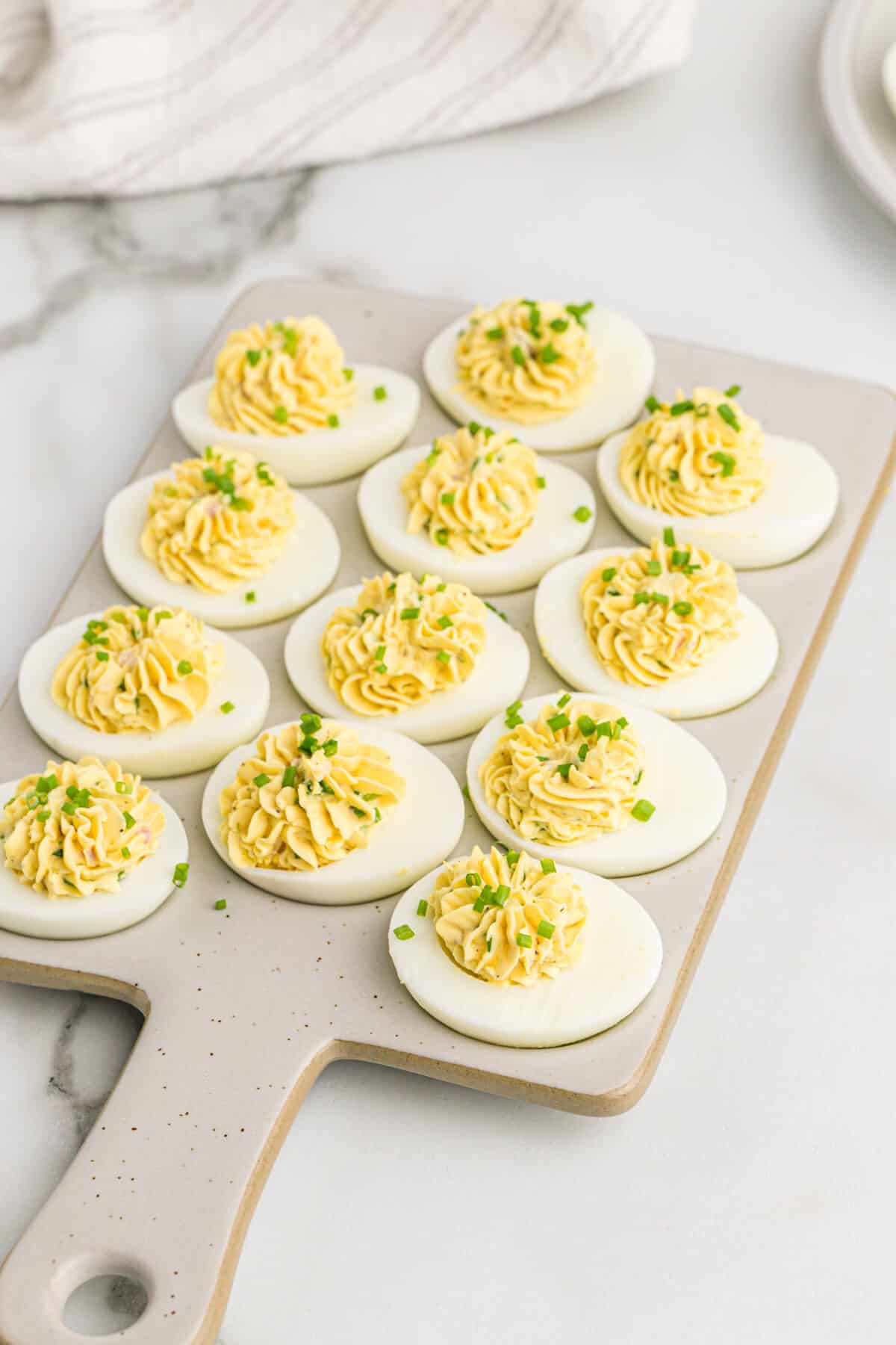 Devilish eggs on a grey cutting board.