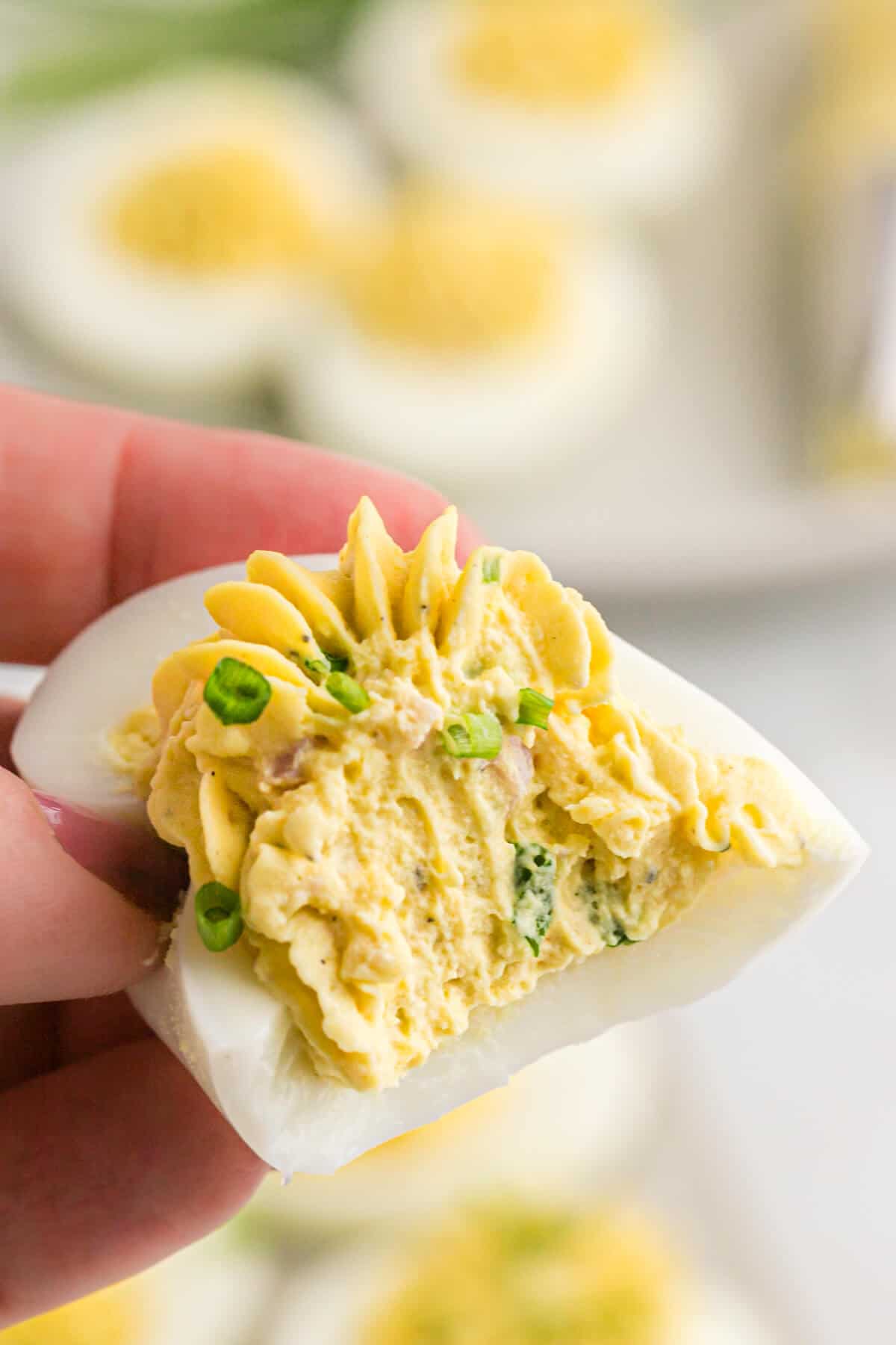 A hand holding a Devilish egg with a bite out of it.
