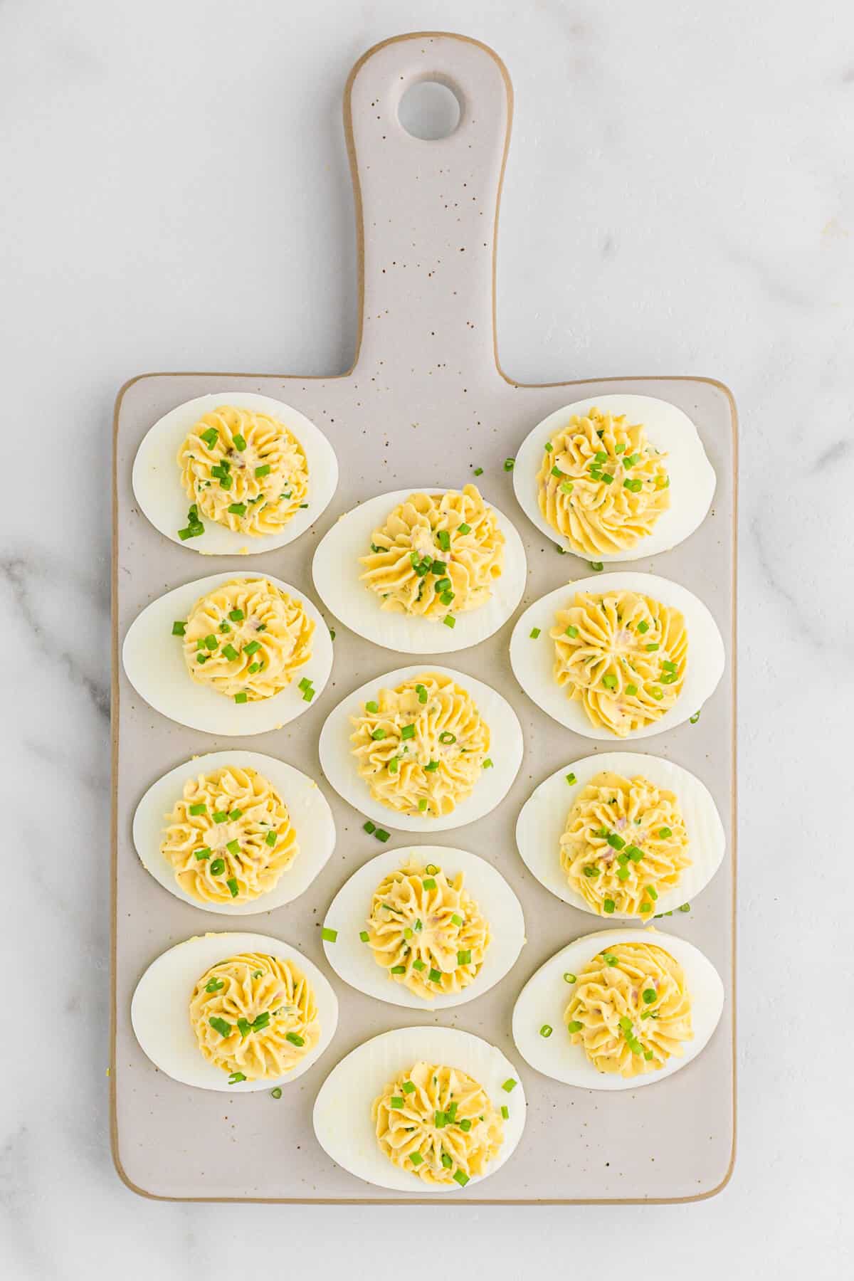 Devilish eggs on a grey cutting board.