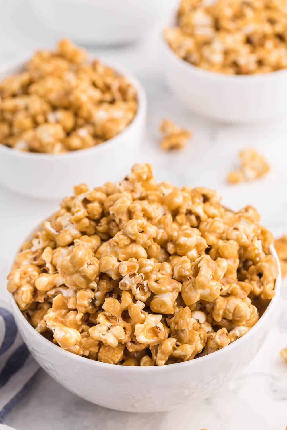 3 white bowls of caramel marshmallow popcorn