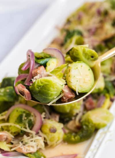 Brussel sprouts with lemon and pancetta on a serving spoon.