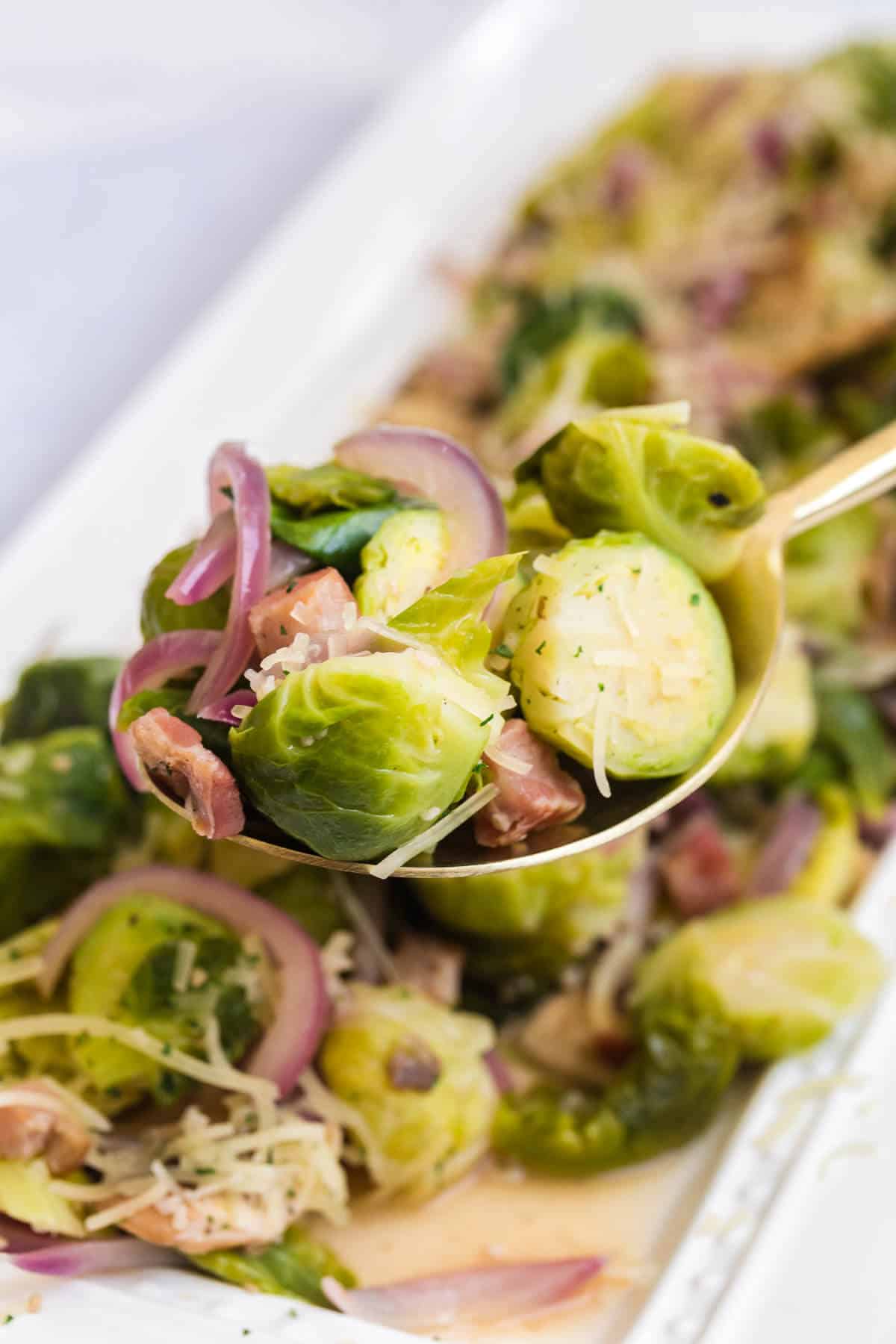 Brussel sprouts with lemon and pancetta on a serving spoon.