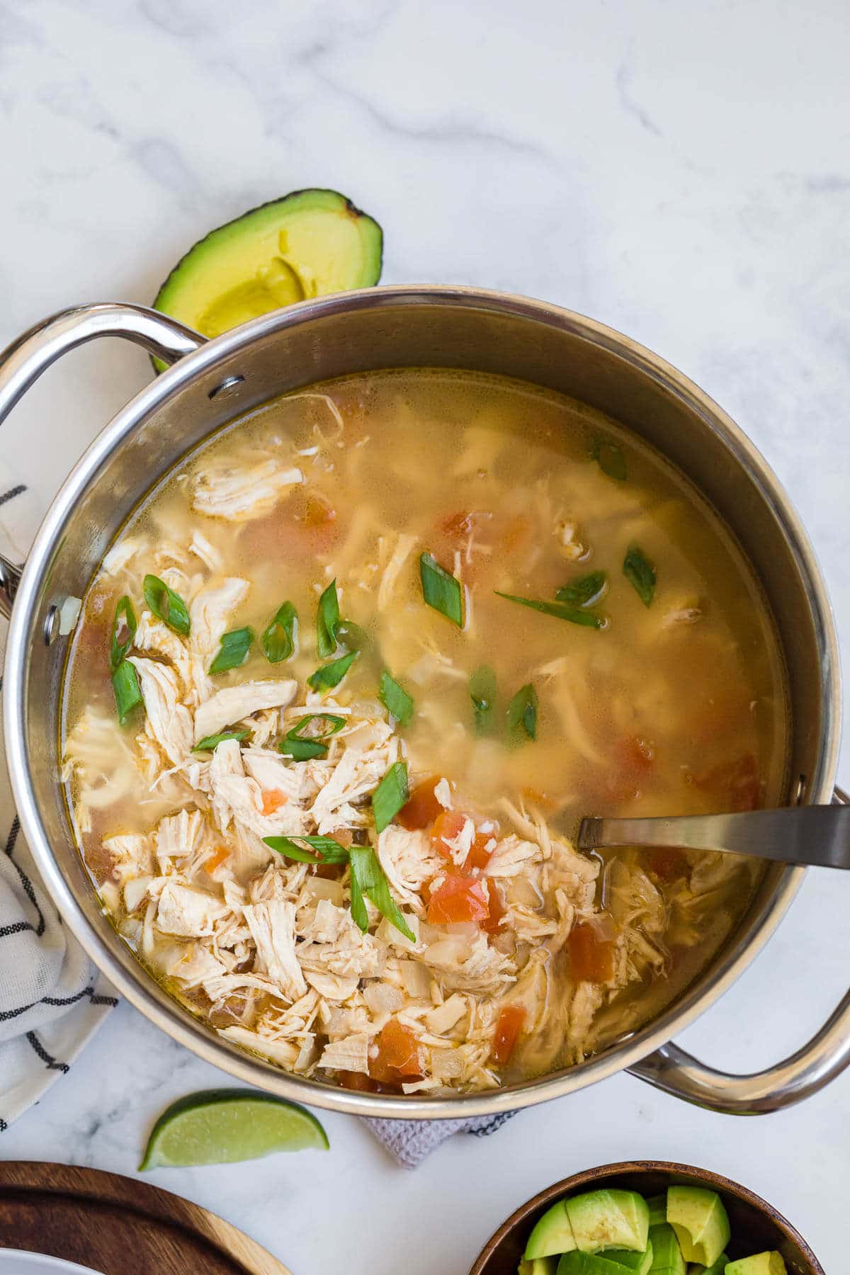 Chicken lime soup in a pot with a soup ladle.