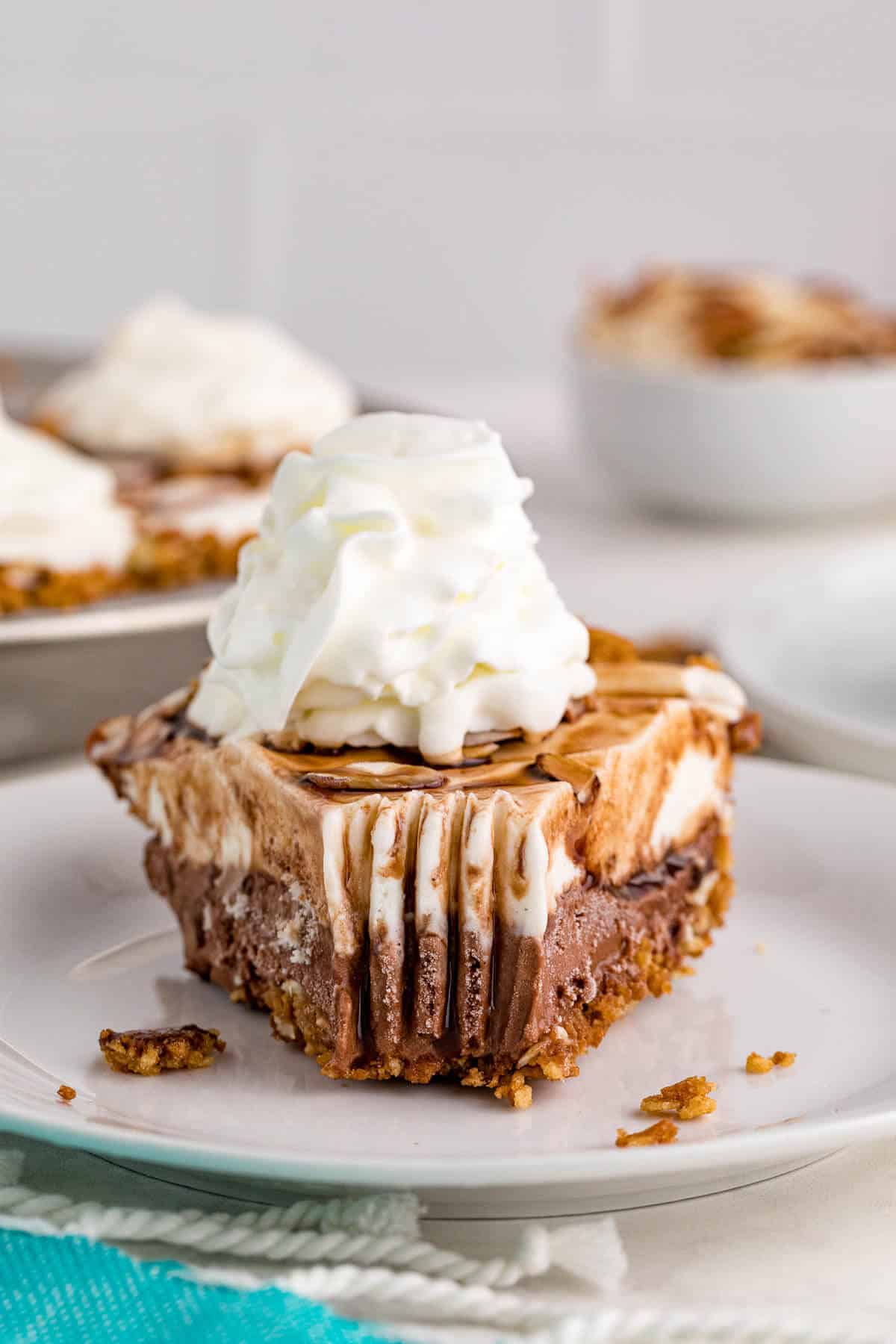 Ice cream pie slice on a plate with a bite off the end.