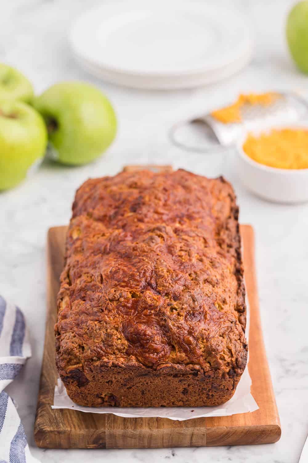 A loaf of apple cheddar bread on a cutting board