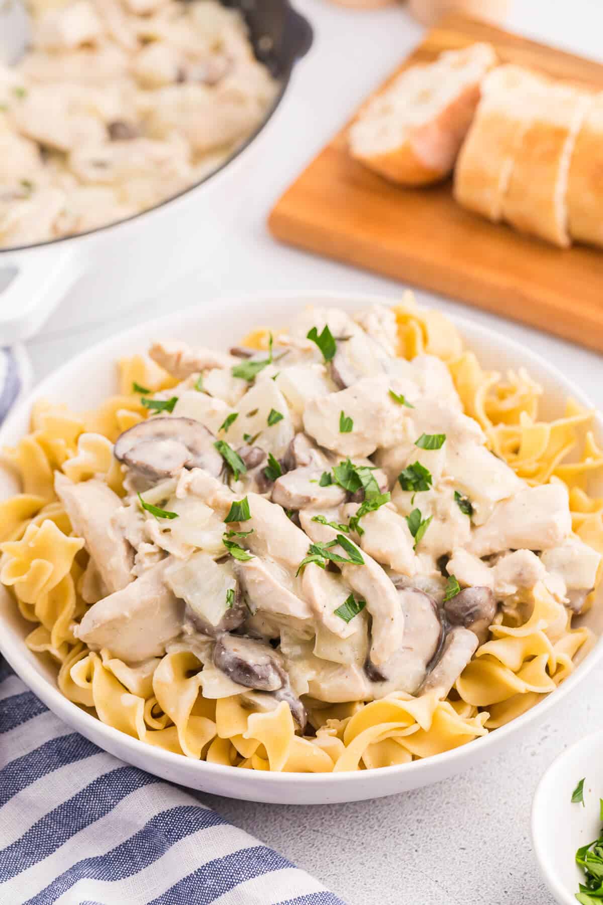 Creamy garlic chicken with noodles in a white bowl.