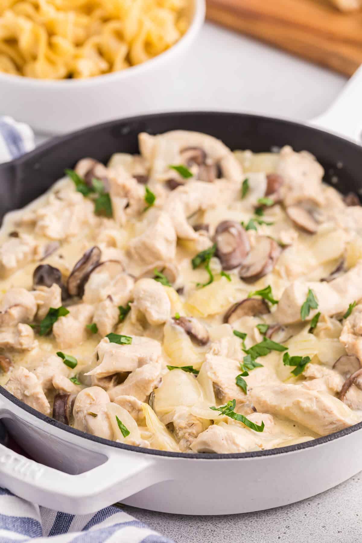 Creamy garlic chicken with noodles in a white skillet.