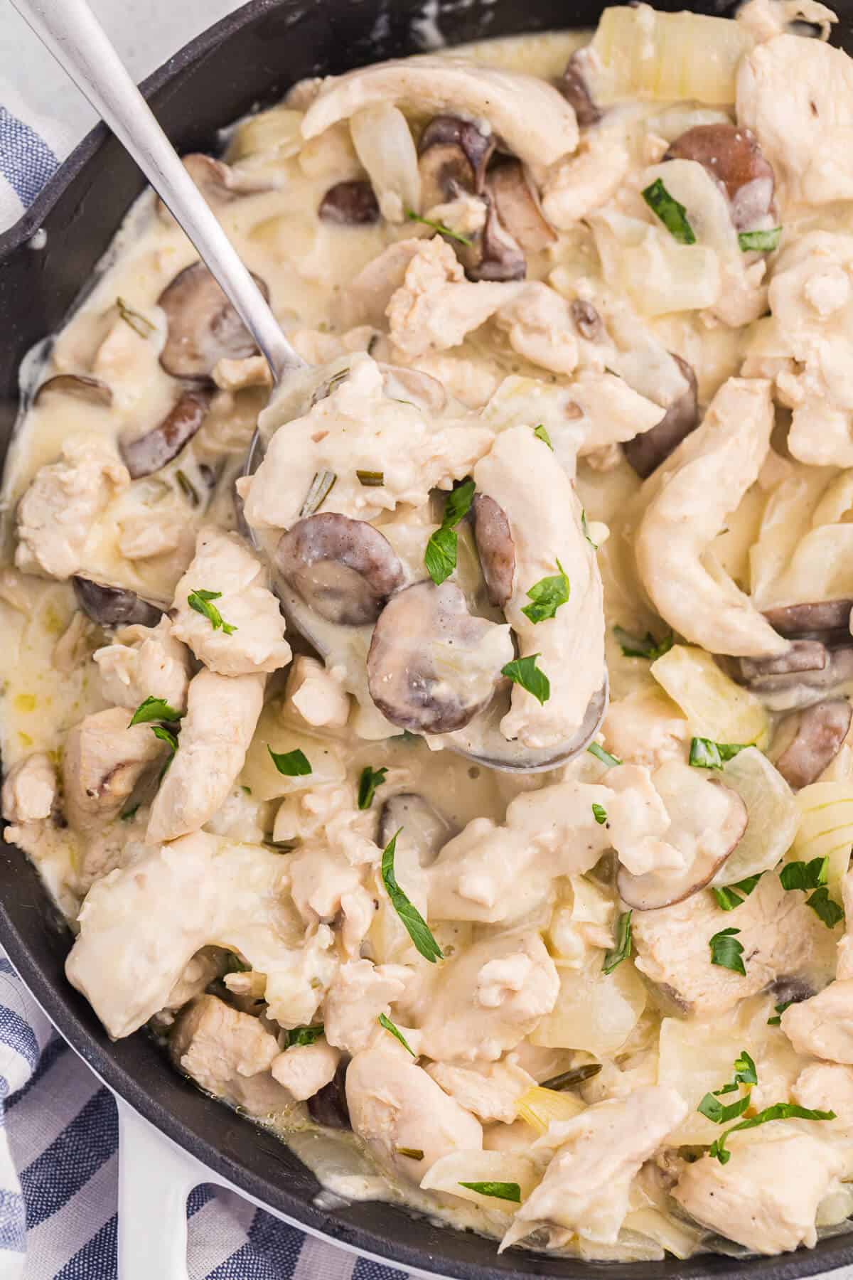 Creamy garlic chicken with noodles in a skillet with a serving spoon.