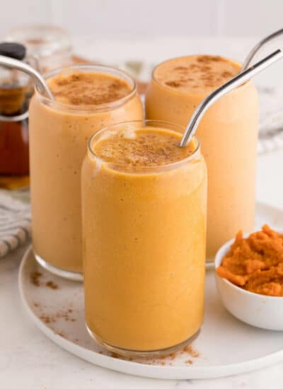 Three pumpkin pie smoothies on a plate.