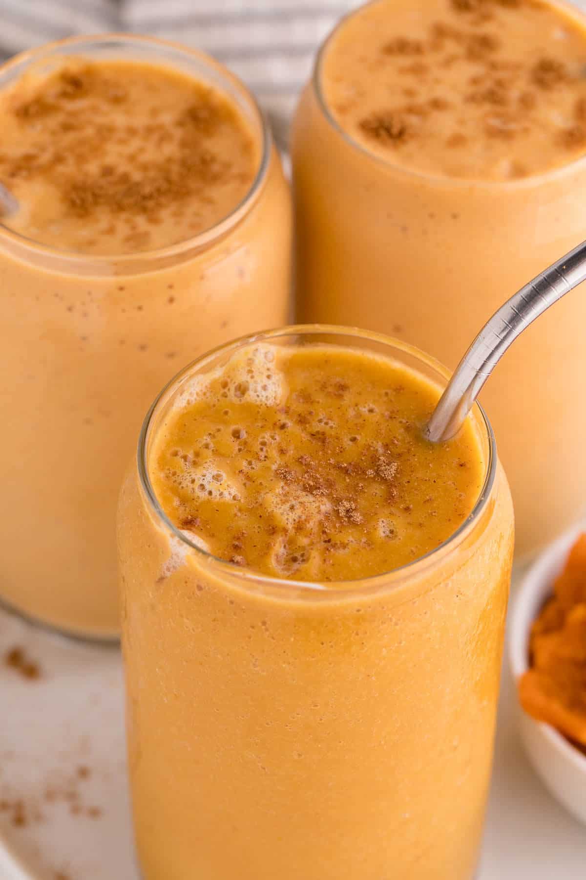 Pumpkin pies smoothie with a metal straw.