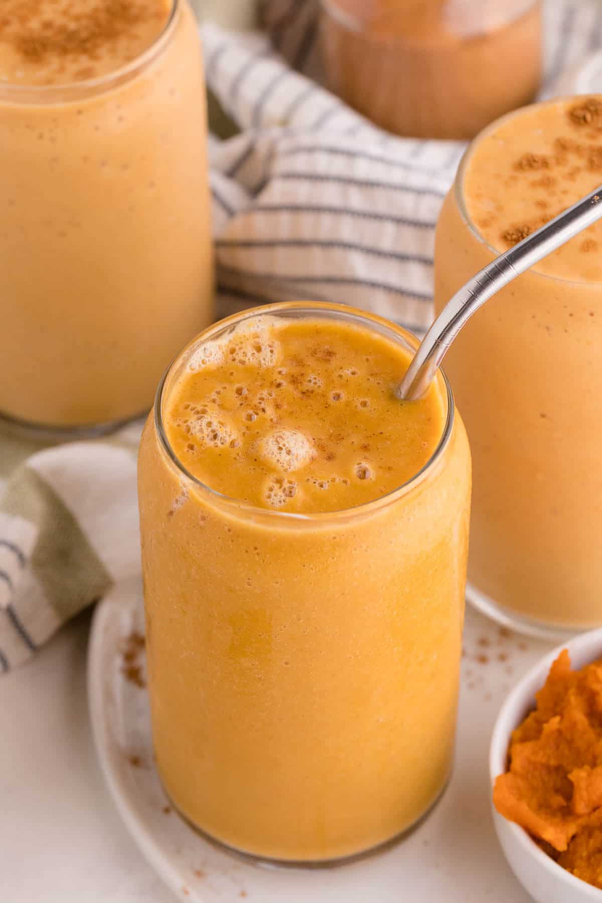 Pumpkin pie smoothie with a metal straw.