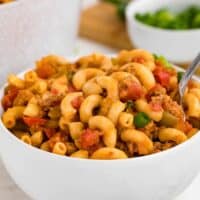 A white bowl and a spoon filled with beef taco pasta.