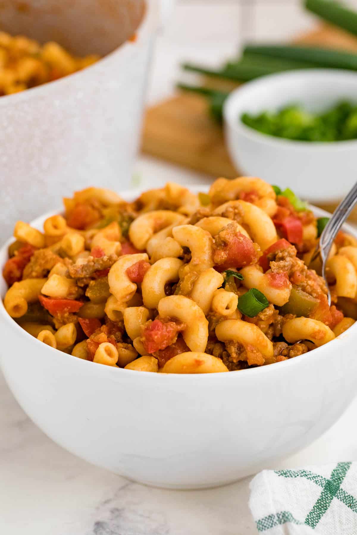 A white bowl and a spoon filled with beef taco pasta.