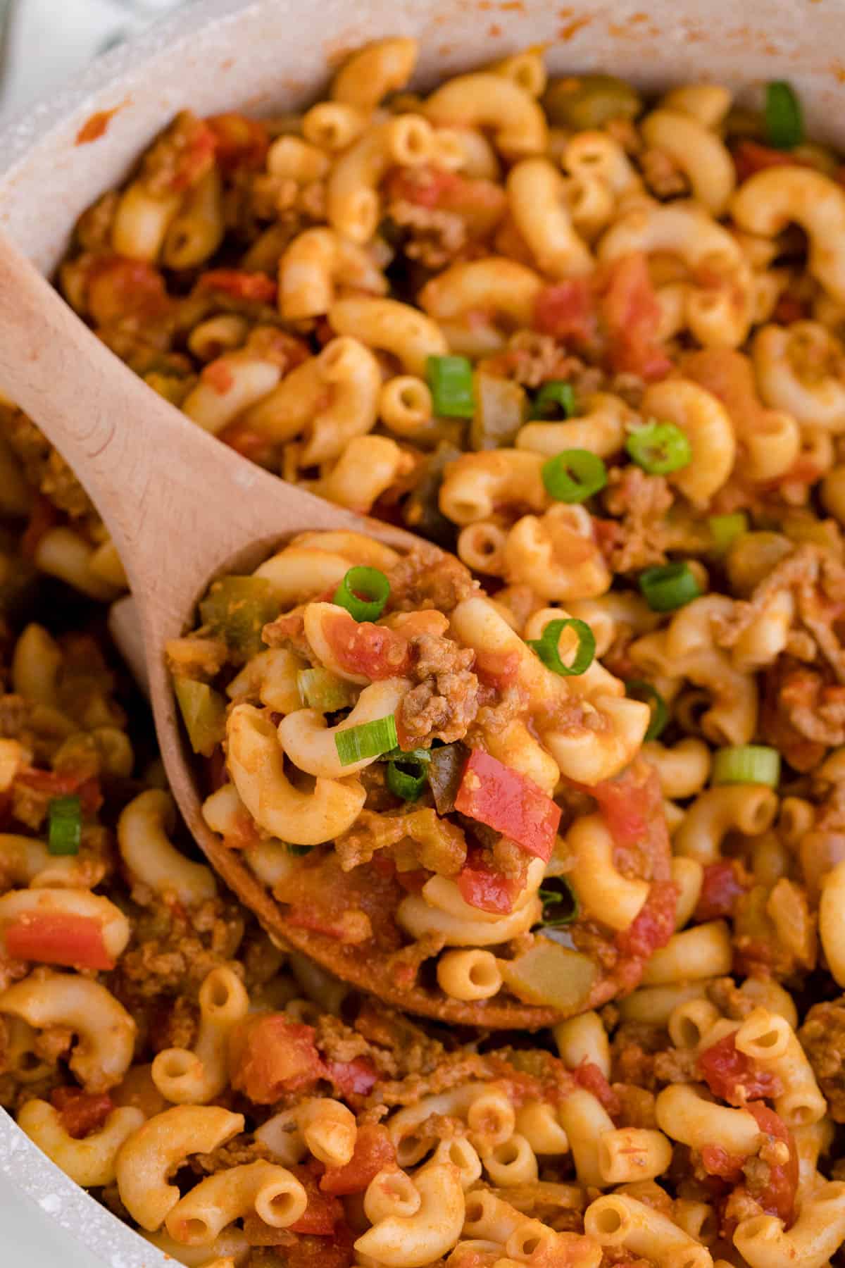 A wooden spoon in a pot of beef taco pasta.