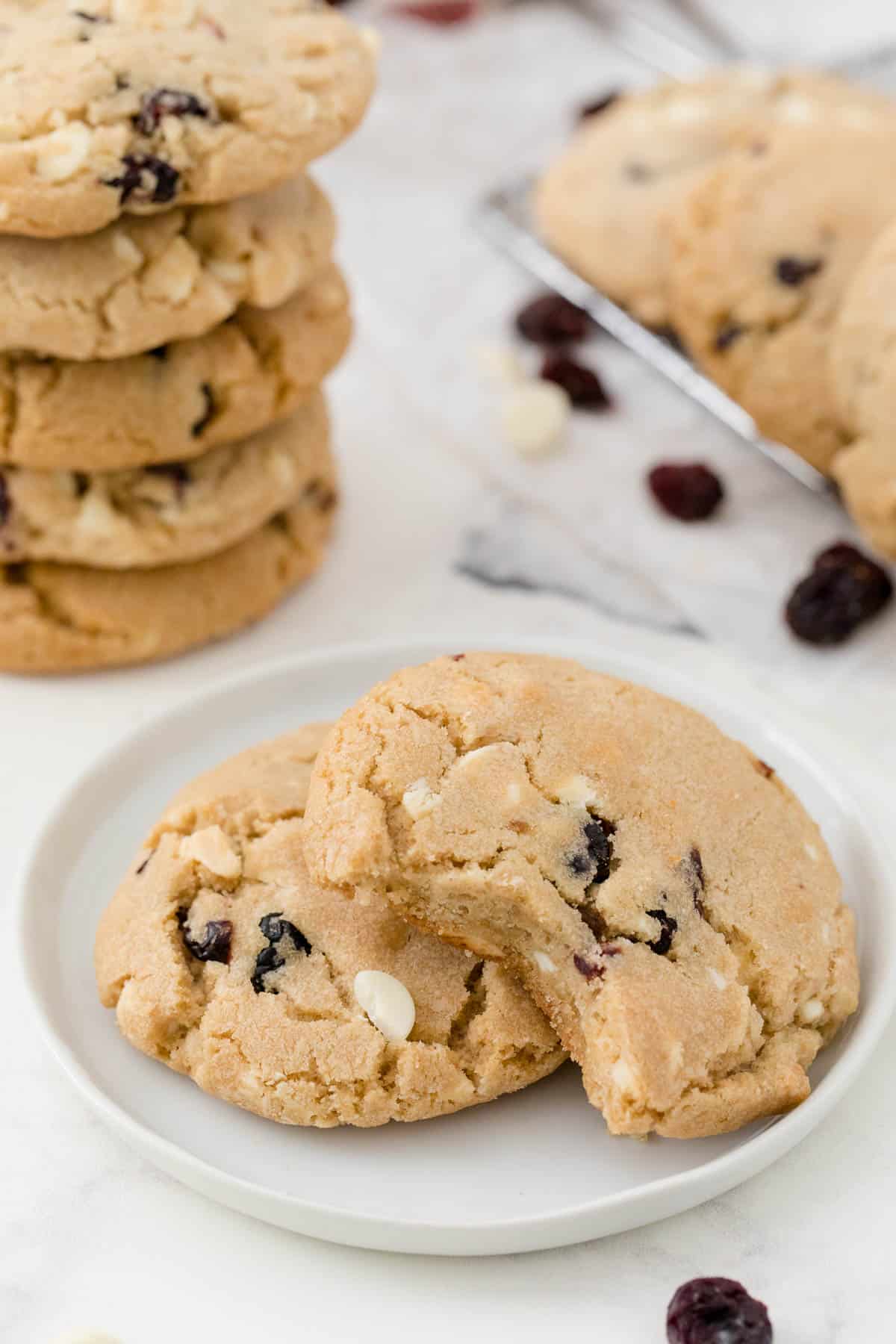 Two white chocolate chunk cranberry cookies on a plate