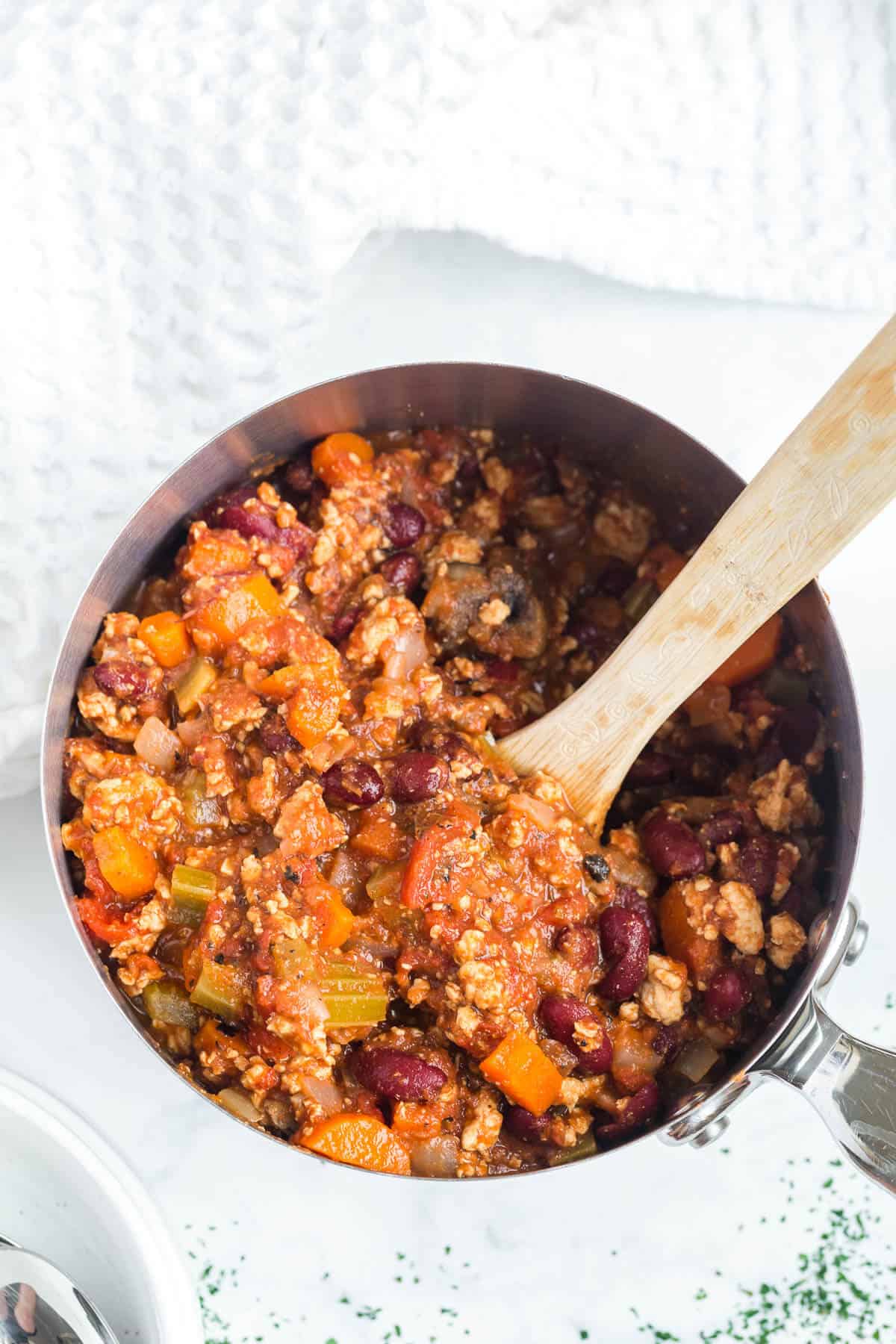 Chicken chili in a pot with a wooden spoon.