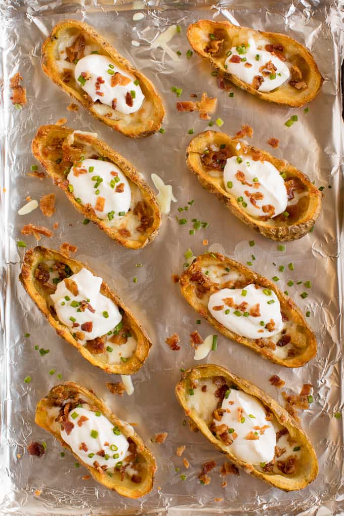 Cheesy Potato Skins - Topped with sour cream, tasty bacon and fresh green onions, this appetizer recipe is a crowd-pleasing classic.