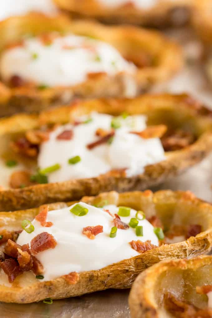 Cheesy Potato Skins - Topped with sour cream, tasty bacon and fresh green onions, this appetizer recipe is a crowd-pleasing classic.