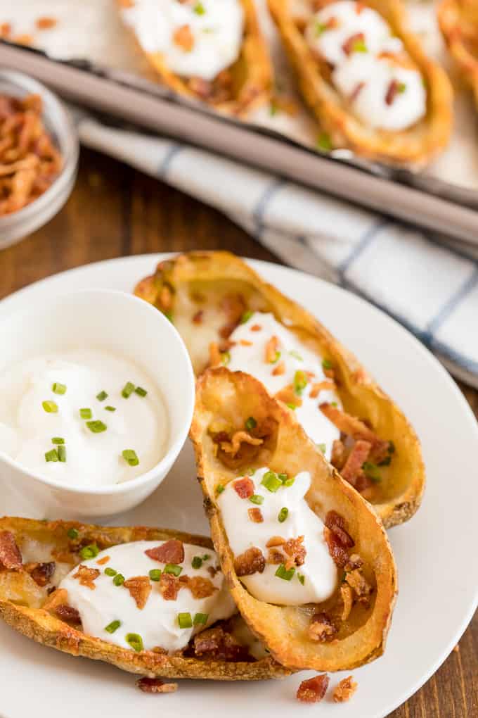 Cheesy Potato Skins - Topped with sour cream, tasty bacon and fresh green onions, this appetizer recipe is a crowd-pleasing classic.