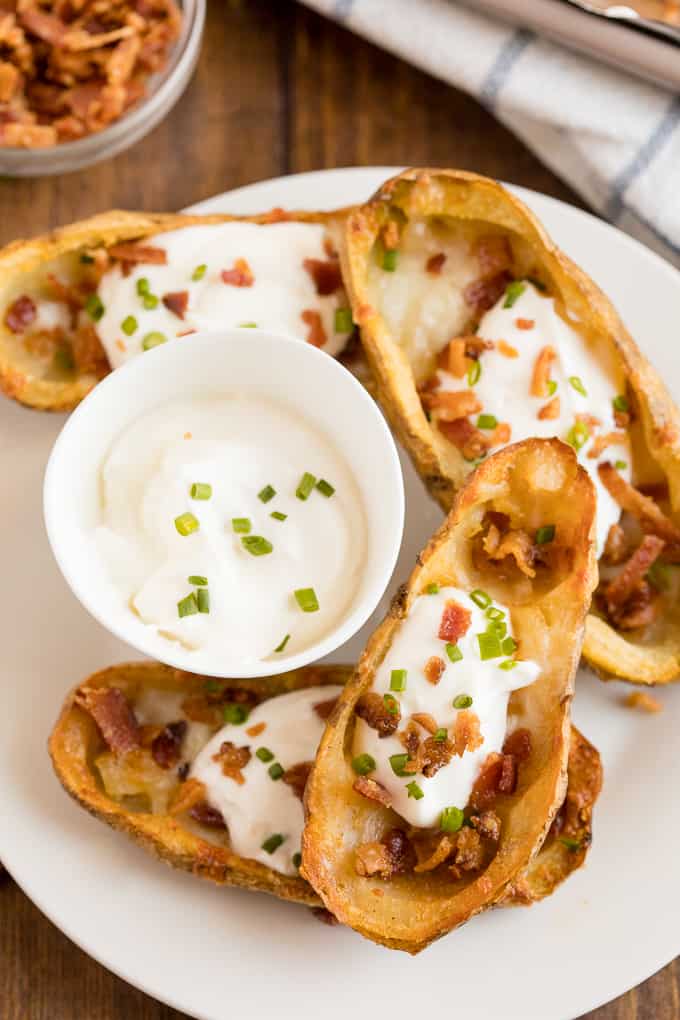 Cheesy Potato Skins - Topped with sour cream, tasty bacon and fresh green onions, this appetizer recipe is a crowd-pleasing classic.