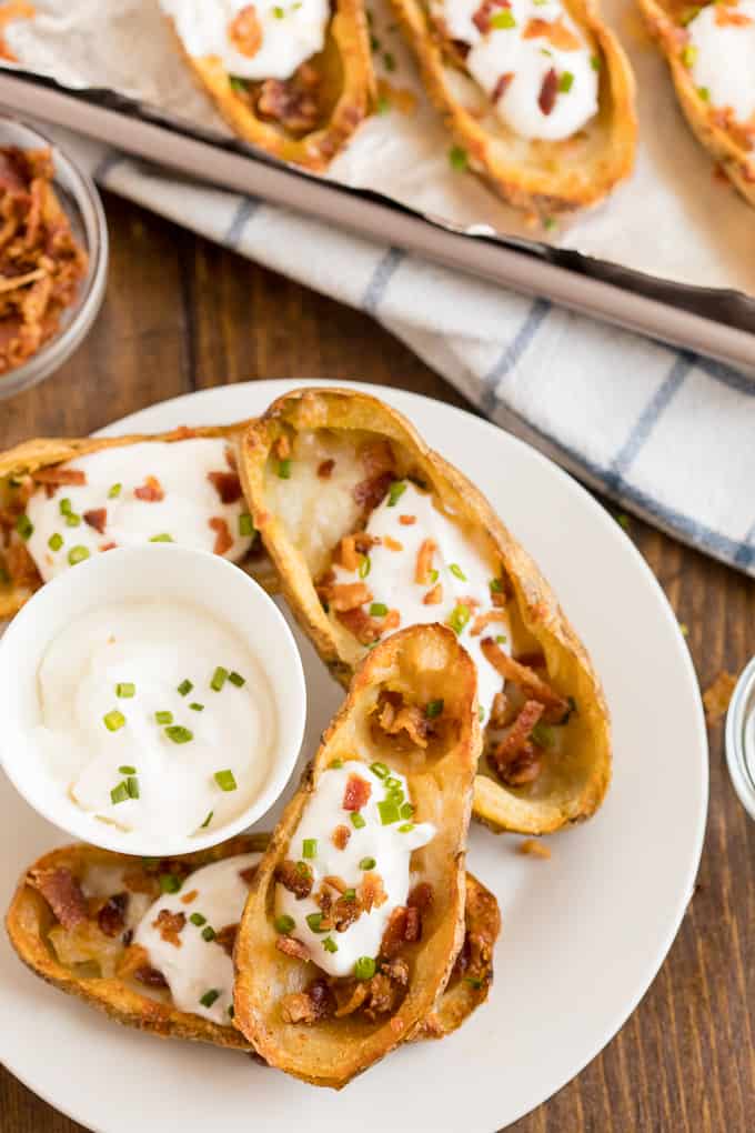 Cheesy Potato Skins - Topped with sour cream, tasty bacon and fresh green onions, this appetizer recipe is a crowd-pleasing classic.