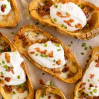Cheesy Potato Skins - Topped with sour cream, tasty bacon and fresh green onions, this appetizer recipe is a crowd-pleasing classic.